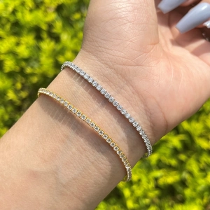 Silver and gold tennis bracelets with round cubic zirconia crystals on wrist closeup