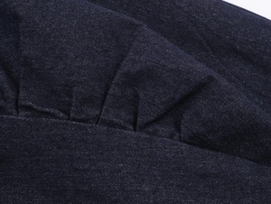 Nahaufnahme der dunkelblauen Denim-Stoffstruktur und der plissierten Handwerkskunst