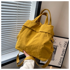 Detail of ginger yellow nylon tote bag showing soft pleated texture and adjustable strap