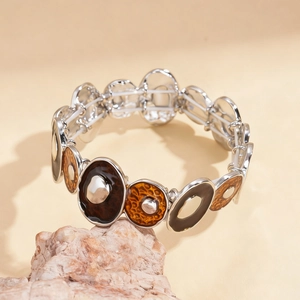 Détail d'un bracelet extensible argenté avec émail marron et orange sur une roche rustique