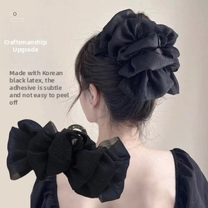 Detail of oversized black pleated hair scrunchies with shimmering bubble texture