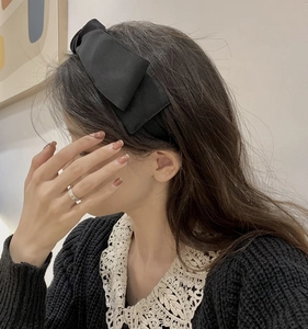 Elegant French style double-layered black bow headband worn by a model in a soft setting