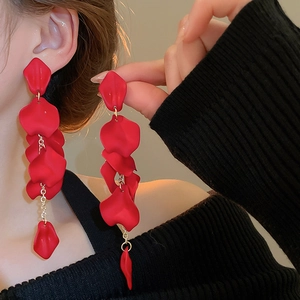 Detailed close-up of long red rose petal tassel earrings worn by a model