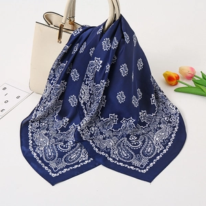 Navy blue silk paisley scarf draped elegantly over a white handbag with tulip decoration