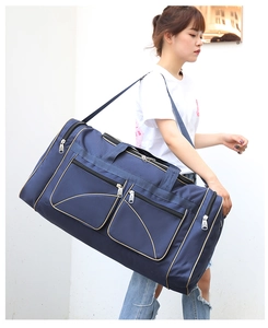 Blue travel duffel bag with gold piping shown being worn on the shoulder by a model
