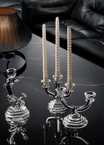 Detail of elegant three-arm glass candle holder with white spiral candles on marble