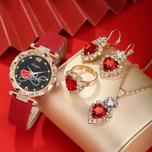 Detail shot of a red watch and gold jewelry set with heart-shaped gems on a red fan