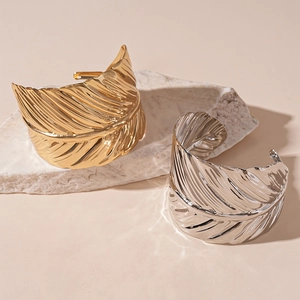 Polished gold and silver leaf pattern open bangles on textured stone display