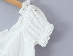Detail of white off-shoulder dress with eyelet embroidery, puff sleeves and ruffles