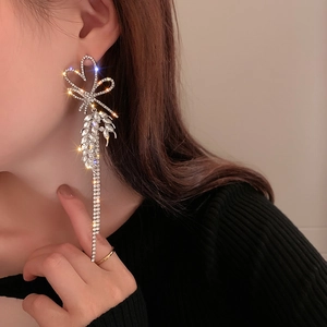 Macro side view of a model wearing sparkling tassel earrings with heart and bow details