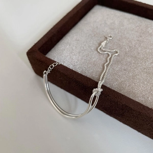 Minimalist silver knotted double-chain bracelet displayed on a brown velvet jewelry tray