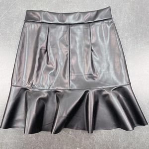 Detail of black PU leather skirt featuring stylish ruffle hem and matte finish texture