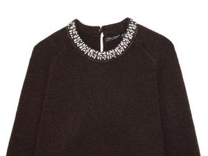 Detail of a chocolate brown knit sweater featuring a luxury crystal beaded neckline