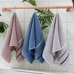 Hanging absorbent cotton towels in pink, blue, and grey with striped bathroom detail