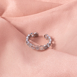 Macro detail of silver honeycomb ring with sparkling zircons on elegant pink silk fabric