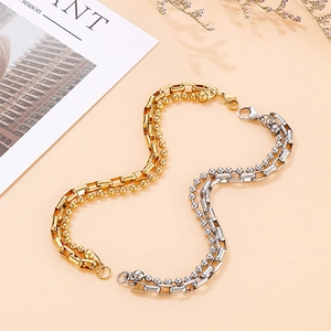 Detailed macro of gold and silver double-layered chain bracelet with lobster clasp