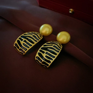 Macro detail of vintage geometric earrings with yellow beads and black striped enamel