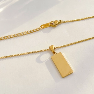 Detail view of the 18K gold-plated lobster clasp and K18 engraving on a square necklace