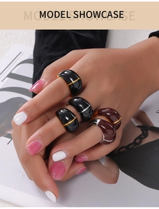 Detail of chunky enamel rings in black and burgundy with gold trim on a model