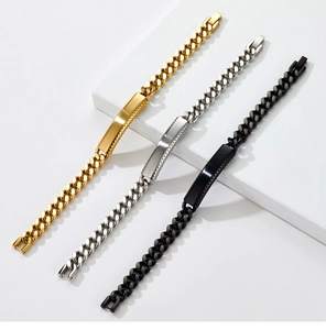 Three Cuban ID bracelets in gold, silver, and black finish on white stone display