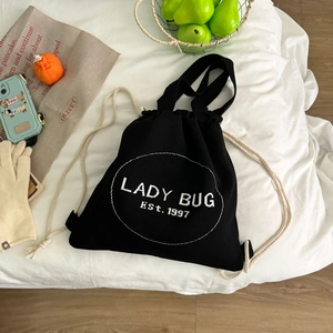 Flachbild des schwarzen Canvas-Kordelzug-Rucksacks mit Lady-Bug-Print auf weißem Bett