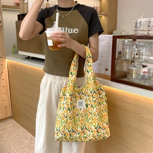 Dettaglio della borsa shopper in tela con fiori di tulipano tenuta da una modella