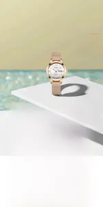Detailed macro view of a rose gold mesh strap quartz watch on a white minimalist platform