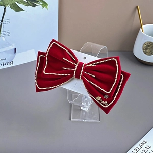 Detail of red velvet bow hair clip with sparkling rhinestone trim and golden pendant