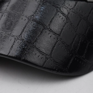 Vue macro de la texture brillante en cuir de crocodile noir sur un chapeau élégant