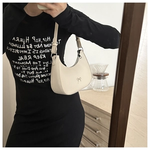 Mirror selfie showing the chic beige crescent shoulder bag with silver bow detail