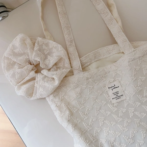 Close-up of beige floral lace embroidery on canvas tote bag with matching scrunchie