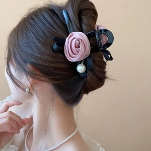 Detail of elegant black hair claw with pink rose, black ribbon and pearl pendant