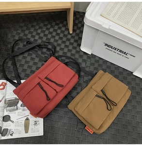 Flat lay of durable nylon messenger bags in brick red and khaki with adjustable straps