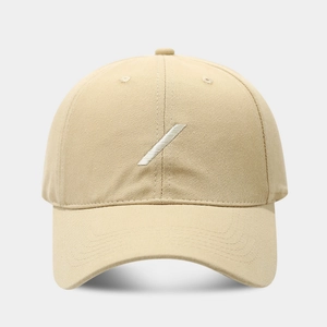 Detailed close-up showing the diagonal white embroidery on a beige cotton baseball cap