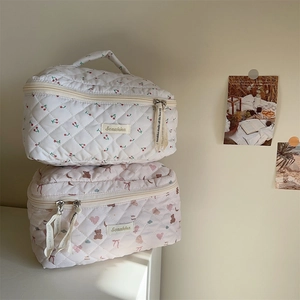 Close-up of quilted cosmetic bags with cute cherry and bear prints and brand woven labels