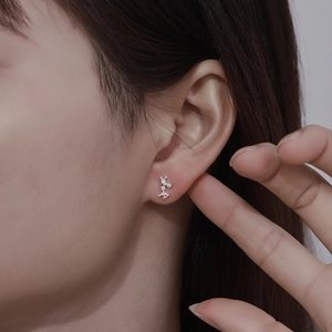Close-up of 999 sterling silver zodiac stud earring with sparkling zircons on female ear