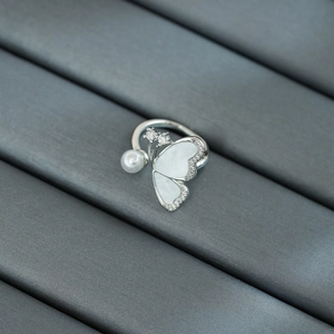 Détail d'une bague papillon en argent avec nacre blanche et une perle ronde délicate