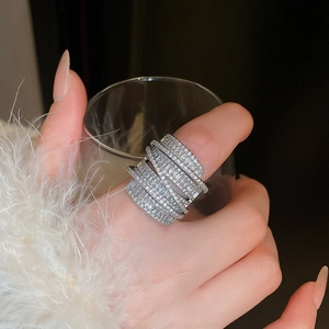 Macro shot of silver wide band wrap ring with zircon pave stones on female hand