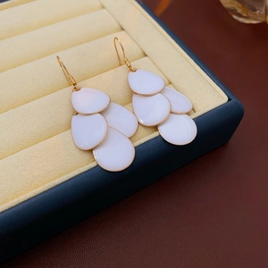 Macro shot of white tiered leaf tassel earrings in a jewelry box with golden hooks