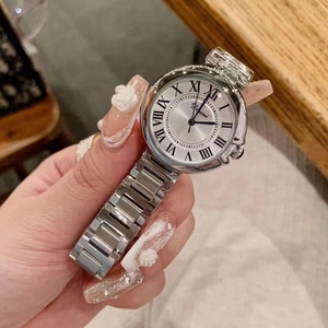 Detail of silver ladies watch featuring Roman numerals and a metallic chain strap