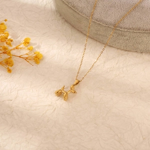 Detail of a shiny golden balloon dog pendant on a necklace with warm studio lighting