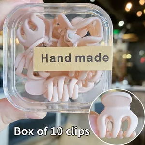 Detalle de un juego de 10 mini pinzas para el cabello rosa mate en una caja transparente