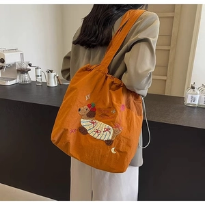 Close-up of caramel drawstring tote bag featuring cute dog embroidery and wide strap