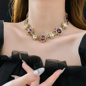 Detail of vintage gold necklace with purple and amber crystals on a model's neck