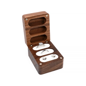 Detailed view of three-slot walnut wood ring box with velvet lining and jewelry inside
