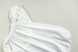 Close-up of white one-shoulder neckline with elegant ruched folds and premium stitching