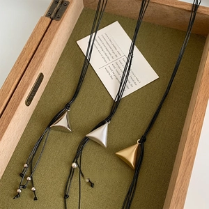 Detailed view of three geometric triangular pyramid pendants in silver and gold metal finishes