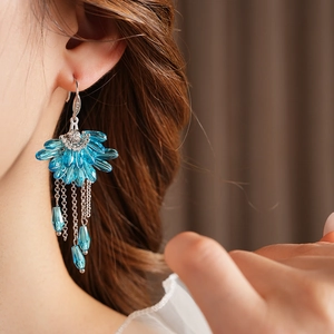 Détail de boucles d'oreilles bohèmes en argent avec cristaux bleus et pompons