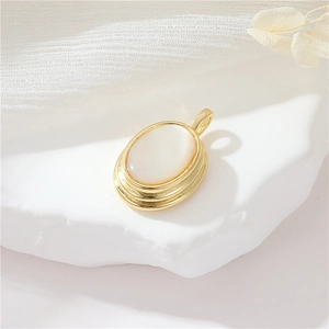 Vintage oval white shell pendant with gold plated tiered frame on white stone background