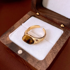 Detail of vintage gold plated open ring with oval tiger eye stone on wood jewelry box